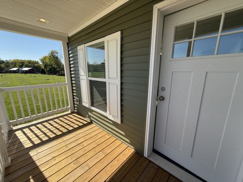 Covered front porch with railing and craftsman-style front door