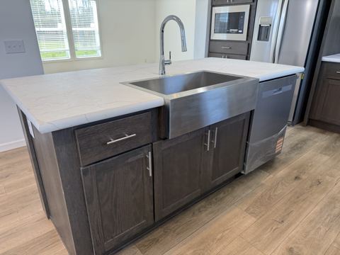 Island with farmhouse-style stainless sink and dishwasher