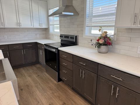 Range with chimney-style hood, subway-tile backsplash and window